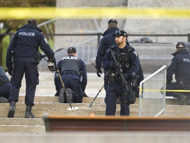 Police using metal detectors sweep the scene Oct 23 at the Cenotaph where a soldier was shot dead Oct 22. The gunman was later killed when he stalked the halls of Parliament Hill.
