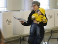 A woman with a child takes her ballot to be recorded at Richelieu-Vanier Community Centre Oct 27 for the City of Ottawa municipal election.