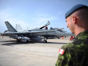 A Canadian soldier looks at a CF-18 as it at Camp Fortin in Trapani, Italy, on September 1, 2011. The Harper government says it will extend the life of its fleet of CF-18 fighters. THE CANADIAN PRESS/Sean Kilpatrick