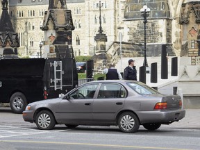 The used Corolla driven by Michael Zehaf-Bibeau in his attack on Parliament  sits parked as police guard the entrance to the Parliament buildings.