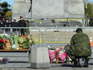 A soldier kneels to read a few of the cards and notes laid in front of the still barricaded memorial. Although much of the area around the National War Memorial and Parliament is still blocked off with police barriers, people were allowed to pay their respects Thursday, laying flowers and notes for the soldier killed in the terrorist attack Wednesday in Ottawa.