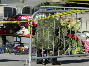 A soldier kneels to read a few of the cards and notes laid in front of the still barricaded memorial. Although much of the area around the National War Memorial and Parliament is still blocked off with police barriers, people were allowed to pay their respects Thursday, laying flowers and notes for the soldier killed in the terrorist attack Wednesday in Ottawa.