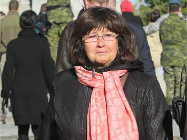 A woman leaves flowers at the site in tears. Although much of the area around the National War Memorial and Parliament is still blocked off with police barriers, people were allowed to pay their respects Thursday, laying flowers and notes for the soldier killed in the terrorist attack Wednesday in Ottawa.