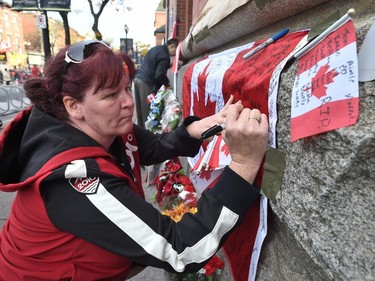 A woman writes words of words of condolence on a Canadian flag for Cpl. Nathan Cirillo before his funeral in Hamilton.