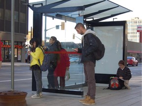 Alan Trahan, 24, sits on the concrete reading school work as he waits for the bus in a new shelter on Rideau Street. He wants to see a bench added.