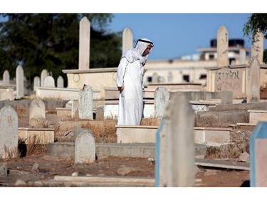 An elderly Palestinian man stands above a grave of one of his relatives in a cemetery next to Hebrew graffiti during the Eid al-Adha holiday in Gaza City, Saturday, Oct. 4, 2014. Muslims around the world Saturday celebrated Eid al-Adha to commemorate the willingness of the prophet Ibrahim - or Abraham as he is known in the Bible - to sacrifice his son in accordance with God's will, though in the end God provides him a sheep to sacrifice instead. The major Muslim holiday coincides this year with the Jewish holiday of Yom Kippur, the first time this has happened since 1981.