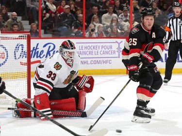 Chris Neil #25 of the Ottawa Senators reaches for the loose puck as Scott Darling #33 of the Chicago Blackhawks guards the net.