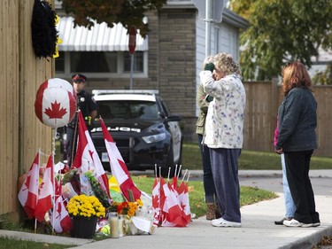 A woman gives a salute after visiting the small memorial that has been growing adjacent to the home of Nathan Cirillo in Hamilton, Ont., on Friday, Oct. 24, 2014. Cpl. Nathan Cirillo was killed by an armed gunman on Parliament Hill early on Wednesday morning.
