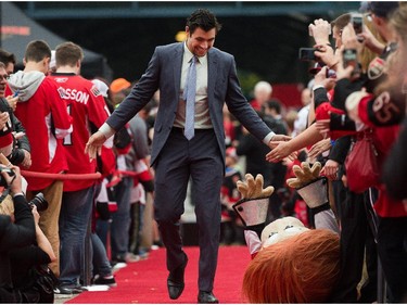 Cody Ceci laughs at Spartacat lying on the ground while being greeted on the red carpet.