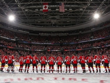 Members of the Ottawa Senators stand at the blue line during the singing of the national anthems.