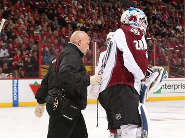 A trainer helps as Reto Berra #20 of the Colorado Avalanche leaves the game after a first period injury.