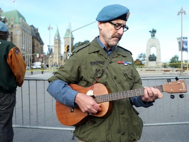 Corporal Joseph Crowley (right) plays "Give peace a chance" in front of the memorial, where he laid flowers with friend and fellow veteran, Doug Bannerman (left). Although much of the area around the National War Memorial and Parliament is still blocked off with police barriers, people were allowed to pay their respects Thursday, laying flowers and notes for the soldier killed in the terrorist attack Wednesday in Ottawa.
