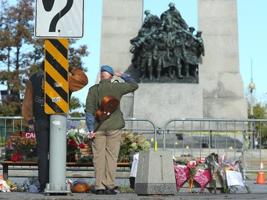 Corporal Joseph Crowley salutes in front of the memorial, where he laid flowers with friend and fellow veteran, Doug Bannerman (left). Although much of the area around the National War Memorial and Parliament is still blocked off with police barriers, people were allowed to pay their respects Thursday, laying flowers and notes for the soldier killed in the terrorist attack Wednesday in Ottawa.