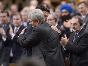 Prime Minister Stephen Harper hugs Liberal Party Leader Justin Trudeau in the House of Commons on Thursday, one day after a gunman stormed Parliament Hill.