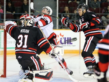 Erik Bradford takes a high stick from Billy Jenkins in front of goalie Brent Moran but no call was made in the first period as the Ottawa 67's take on the Niagara Ice Dogs in their home opener at the renovated TD Place arena.