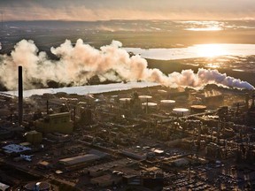 The setting sun reflects off a tailings pond behind Syncrude's oilsands upgrading facility north of Fort McMurray, Alta. in June, 2013.
