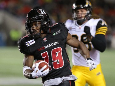 Running back Roy Finch #19 of the Ottawa Redblacks runs back the ball as wide receiver Giovanni Aprile #88 of the Hamilton Tiger-Cats chases after him in the first quarter.