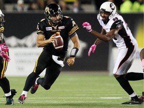 Hamilton Tiger-Cats' Zach Collaros carries the ball between Ottawa Redblacks' defenders during first half CFL action.