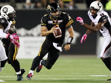 Hamilton Tiger-Cats' Zach Collaros carries the ball between Ottawa Redblacks' defenders during first half CFL action in Hamilton, Ontario on Friday, Oct. 17, 2014.