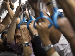 In this Sept. 17, 2014, photo, a man closes his eyes as he stands with other commuters in a crowded metro car during rush hour in Rio de Janeiro. On packed subways and crowded highways, billions of people worldwide participate in the daily commute to and from work.