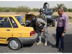 Iraqi federal policemen search a car at a checkpoint in Baghdad, Iraq, Saturday, Oct. 11, 2014. On the western edge of Iraq�s capital, Islamic State group militants battle government forces and exchange mortar fire, only adding to the sense of siege in Baghdad despite airstrikes by a U.S.-led coalition. Military experts say the Sunni militants, won�t be able to fight through both government forces and Shiite militias now massed around the capital, It does, however, put them in a position to wreak havoc in Iraq�s biggest city, with its suicide attacks and other assaults.