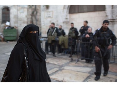 A Palestinian Muslim woman walks past Israeli policemen on her way to the Al-Aqsa Mosque compound for the morning Eid al-Adha prayer, on October 4, 2014, in Jerusalem's old city. Israel is in security lockdown for the Jewish fast of Yom Kippur, which is coinciding with the Muslim festival of Eid al-Adha for the first time in three decades. The concurrence of the holy days has not occurred for 33 years because the two faiths use different lunar calendars.