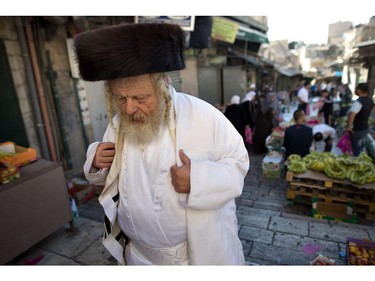 An Ultra-orthodox Jewish man returning from Yom Kippur prayers in the Western Wall walks past Palestinian Muslims on their way to the Al-Aqsa Mosque compound for the Eid al-Adha prayers, on October 4, 2014, in Jerusalem's old city, where the two holy sites are located. Israel is in security lockdown for the Jewish fast of Yom Kippur, which is coinciding with the Muslim festival of Eid al-Adha for the first time in three decades. The concurrence of the holy days has not occurred for 33 years because the two faiths use different lunar calendars.