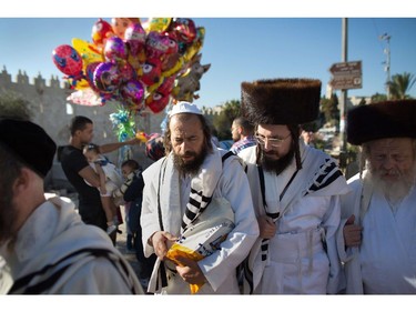Ultra-orthodox Jews returning from Yom Kippur prayers in the Western Wall walk past Palestinian Muslims (back-L) celebrating Eid al-Adha, on October 4, 2014, in Jerusalem's old city. Israel is in security lockdown for the Jewish fast of Yom Kippur, which is coinciding with the Muslim festival of Eid al-Adha for the first time in three decades. The concurrence of the holy days has not occurred for 33 years because the two faiths use different lunar calendars.