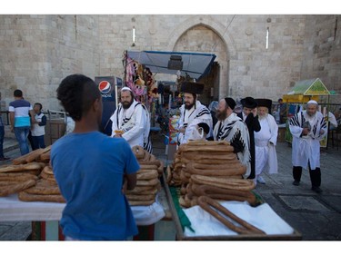 Ultra-orthodox Jews (C) returning from Yom Kippur prayers in the Western Wall walk past Palestinian Muslims celebrating Eid al-Adha, on October 4, 2014, in Jerusalem's old city. Israel is in security lockdown for the Jewish fast of Yom Kippur, which is coinciding with the Muslim festival of Eid al-Adha for the first time in three decades. The concurrence of the holy days has not occurred for 33 years because the two faiths use different lunar calendars.