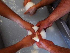 An employee makes buffalo mozzarella at the Tenuta Vannulo dairy farm in Capaccio on September 3, 2013.