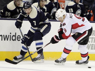 Columbus Blue Jackets' Jack Johnson, left, passes the puck in front of Ottawa Senators' Milan Michalek, of the Czech Republic, during the first period.