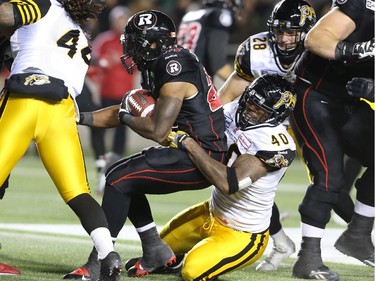 Jeremiah Johnson (27) of the Ottawa Redblacks is tackled by Eric Norwood (40) of the Hamilton Tiger-Cats during first half CFL action.