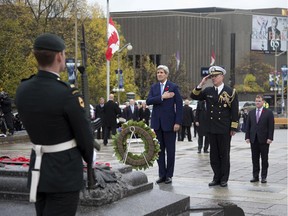 Secretary of State John Kerry, left, and U.S. Naval Attache, Capt. Charles J. Cassidy, pay their respects after placing a wreath at the Tomb of the Unknown Soldier, as Canadian Foreign Minister John Baird, right, watches during a ceremony at the National War Memorial in Ottawa, Canada, Tuesday, Oct. 28, 2014.