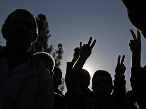 Kurdish mourners flash the V-sign as they chant slogans during the funeral of Kurdish fighters Hanim Dabaan, 20,  Idris Ahmad, 30, and Mohammed Mustafa, 25, killed in the fighting with the militants of the Islamic State group in Kobani, Syria, at a cemetery in Suruc, on the Turkey-Syria border, Tuesday, Oct. 21, 2014.