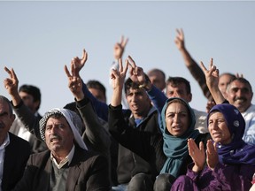 Kurdish people flash the V-sign as they sit in formation to form the initials of the People's Protection Units, or YPG, the main Kurdish militia in Syria, on a hilltop on the outskirts of Suruc, at the Turkey-Syria border, overlooking Kobani, Syria, just over the border, in support of Syrian Kurds fighting the militants of Islamic State group, Wednesday, Oct. 15, 2014. Kobani, also known as Ayn Arab, and its surrounding areas, has been under assault by extremists of the Islamic State group since mid-September and is being defended by Kurdish fighters.