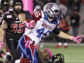 Linebacker Jasper Simmons #31 of the Ottawa Redblacks loses his helmet as he tackles running back Jean-Christophe Beaulieu #46 of the Montreal Alouettes.