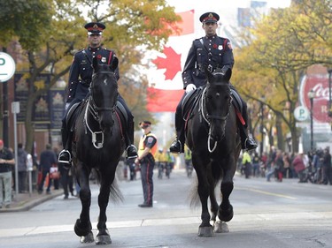 Mounted Hamilton police ride down a street as people gather for the funeral procession of Cpl. Nathan Cirillo.
