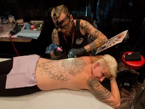 Nicholas Leonard tattoos the back on Jaime Ava Jones of Ottawa as the annual Ottawa Gatineau Tattoo Expo got underway.