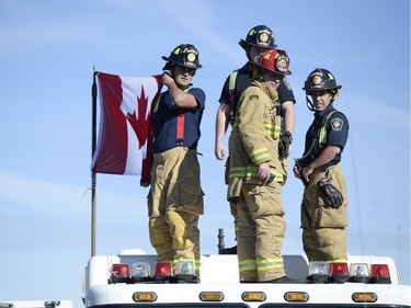 Ottawa Firefighters holds up Canadian flag on top of a firetruck at Bankfield at the 416 to pay respects as the escort with the body of Nathan Cirillo is transported by hearse from Ottawa via Highway of Heroes to Hamilton on Friday, Oct. 24, 2014.