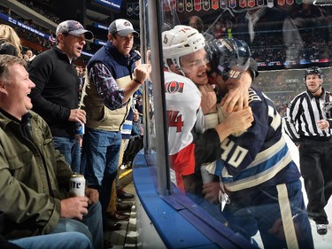 Fans watch as Mark Borowiecki #74 of the Ottawa Senators and Jared Boll #40 of the Columbus Blue Jackets fight against the glass during the first period.