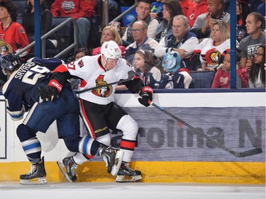 David Savard #58 of the Columbus Blue Jackets attempts to hip check Curtis Lazar #27 of the Ottawa Senators as he reaches for a loose puck during the second period.