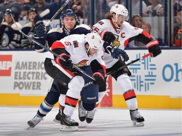 Marko Dano #56 of the Columbus Blue Jackets battles with Bobby Ryan #6 and Erik Karlsson #65 of the Ottawa Senators while skating after a loose puck during the third period.