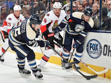 Mark Borowiecki #74 of the Ottawa Senators and Jack Skille #10 of the Columbus Blue Jackets watch as Mark Letestu #55 of the Columbus Blue Jackets attempts to gain possession of the puck during the third period.