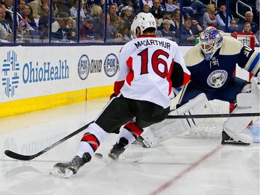 Curtis McElhinney #30 of the Columbus Blue Jackets pokes the puck away from Clarke MacArthur #16 of the Ottawa Senators during the third period.