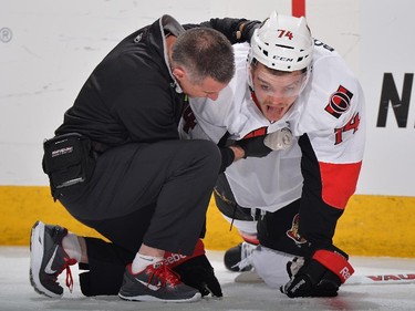 Mark Borowiecki #74 of the Ottawa Senators is helped up by Head Athletic Trainer Gerry Townend after being hit from behind by Corey Tropp #26 of the Columbus Blue Jackets during the third period. Tropp was given a major penalty and a game misconduct for checking from behind.