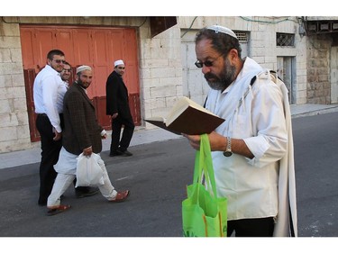 Palestinian Muslim worshipers (L) walk past a Jewish worshiper near the al-Ibrahimi mosque, or the Tomb of the Patriarch, a religious site to both Muslims and Jews, in the divided West Bank town of Hebron on October 04,2014. The Jewish fast of Yom Kippur is coinciding with the Muslim festival of Eid al-Adha for the first time in three decades. The concurrence of the holy days has not occurred for 33 years because the two faiths use different lunar calendars.