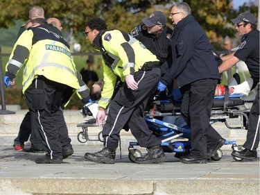 Paramedics and police pull a shooting victim away from the Canadian War Memorial in Ottawa on Wednesday Oct.22, 2014. A Canadian soldier standing guard at the National War Memorial in Ottawa has been shot by an unknown gunman and there are reports of gunfire inside the halls of Parliament.