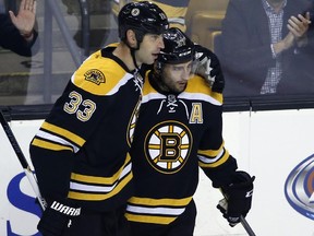 Fans react as Boston Bruins center Patrice Bergeron, right, is congratulated by teammate Zdeno Chara (33) after his goal against the New York Islanders in the first period of an NHL preseason hockey game in Boston, Tuesday, Sept. 30, 2014.