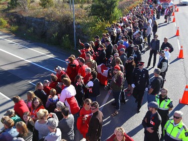 People wait for the procession carrying the remains of Cpl. Nathan Cirillo to pass through Kingston, Ont., on Friday, Oct. 24, 2014. The 24-year-old reservist was gunned down as he stood ceremonial guard at the National War Memorial in Ottawa on Wednesday.