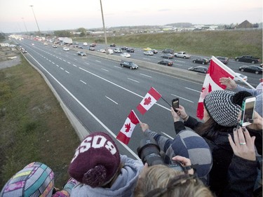 People show their support at the Whites Road overpass in Pickering as a procession of vehicles returns the remains of Cpl. Nathan Cirillo to Hamilton, Thursday October 24, 2014. Cpl. Cirillo was killed while on guard at the National War Memorial in Ottawa.